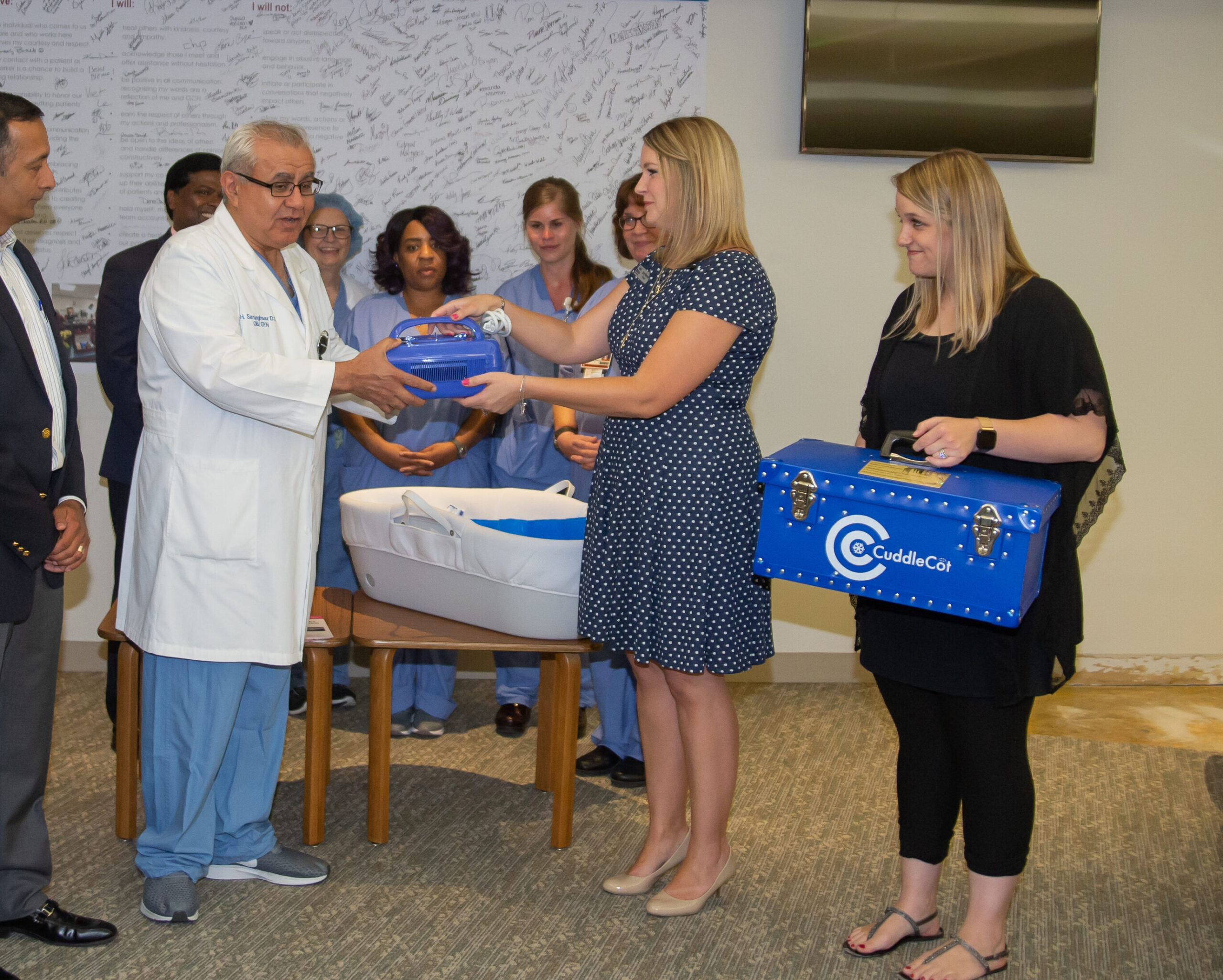 Garden City Hospital CuddleCot Dedication Photo. Ashlie's Embrace founder, Erin Maroon, and loss mom, Leslie Burman, present a CuddleCot to hospital staff during dedication ceremony. (Found on page Hospital Cooling Unit Request)