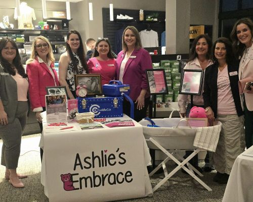 Ashlie’s Embrace founder Erin Maroon and board members with the founders of 100 Women Strong Ohio at their 2026 Giving Circle event, with a CuddleCot on display.