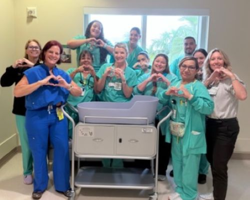 Labor and delivery staff gather around a Caring Cradle donated through Ashlie’s Embrace to Baptist Health Homestead Hospital.