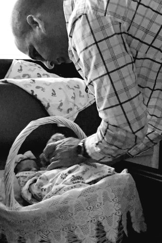 Tony Maroon looking down at his daughter, Ashlie Cathren, as she rests in a basket the day after her birth.